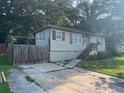 An exterior side view of a single-story home with a sidewalk, driveway, and wooden fence at 633 Tom Read Dr, Marietta, GA 30062