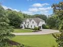 Charming white home nestled on a large lot with a meticulously landscaped yard and mature trees at 590 Arthur Rd, Canton, GA 30115