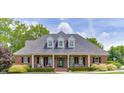 Charming brick home with a covered front porch, black shutters, and landscaped bushes enhancing its traditional appeal at 2623 Lindsey Grace Ln, Buford, GA 30519