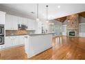 Open-concept kitchen and living area featuring white cabinetry, hardwood floors, and a stone fireplace at 255 Kendemere Pointe, Roswell, GA 30075