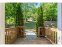 Exterior view from deck with wood railing overlooking a tree lined back yard with a concrete walkway at 1496 Shadowrock Dr, Marietta, GA 30062