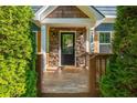 Inviting front porch with stone accents, dark wood door and hardware, and a natural wood porch and railing at 1496 Shadowrock Dr, Marietta, GA 30062