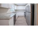 Modern kitchen featuring white cabinets, stainless steel appliances, granite countertops, and light grey flooring at 2091 Moon Drive Sw, Conyers, GA 30094