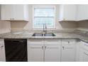 Bright kitchen featuring white cabinets, granite countertops, stainless steel sink and black dishwasher at 2091 Moon Drive Sw, Conyers, GA 30094