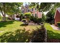 Two-story brick home with mature trees and lush landscaping in a well-maintained yard at 2484 Mossy Branch Dr, Snellville, GA 30078