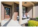 Inviting covered front porch with seating area, a welcome mat and brick accents at 3537 Edenridge Ct, Buford, GA 30519