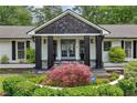 Inviting front porch with stone accents, black pillars, and a meticulously landscaped garden at 5860 Riverwood Dr, Sandy Springs, GA 30328