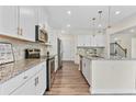 Modern kitchen with white cabinets, granite countertops, stainless steel appliances, and stylish pendant lighting at 3390 Meadow Grass Drive, Dacula, GA 30019