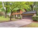 Exterior of a charming home with mature trees, featuring a brick and wood facade and attached garage at 3352 Northbrook Dr, Atlanta, GA 30340