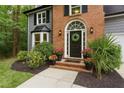 Inviting front entrance with a black door, brick accents, and professionally landscaped plants at 4806 Deer Chase, Powder Springs, GA 30127