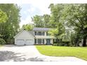 Two-story home with black shutters, light yellow siding, a well-manicured lawn and mature trees at 3707 Dunwoody Club Dr, Atlanta, GA 30350