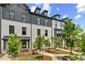 Charming townhome exterior with brick facade, black trim, landscaped yard, and inviting walkways under a partly cloudy sky at 441 Breccia Run, Mcdonough, GA 30253