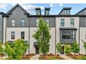 Charming townhome exterior with brick facade, black trim, landscaped yard, and inviting walkways under a partly cloudy sky at 441 Breccia Run, Mcdonough, GA 30253