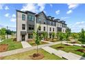Charming townhome exterior with brick facade, black trim, landscaped yard, and inviting walkways under a partly cloudy sky at 441 Breccia Run, Mcdonough, GA 30253