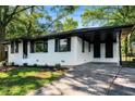 Front exterior with freshly painted white facade, mature trees, and a long driveway leading to a carport at 1207 Ellington Dr, Morrow, GA 30260
