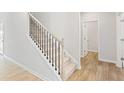 A staircase with neutral walls, black iron railings and light wood flooring leading upstairs at 7175 Brushwood Bend - Lot 36, Lithonia, GA 30058