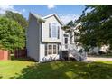 Corner view of a gray two-story home with black shutters and mature trees, situated on a well-maintained lot at 7186 Raintree Loop, Jonesboro, GA 30236