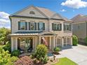 Charming two-story home with white brick, shuttered windows, two-car garage, and covered front porch at 4440 Atwood Dr, Cumming, GA 30040