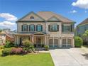 Charming two-story home with white brick, shuttered windows, two-car garage, and professionally landscaped front yard at 4440 Atwood Dr, Cumming, GA 30040