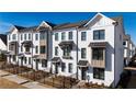 Charming townhomes feature white brick exteriors with gray accents, modern windows, and landscaped front yards at 506 Healy Dr # 74, Cumming, GA 30040