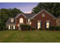 Charming brick and siding home with a well-manicured lawn and mature landscaping at dusk at 2525 Highbrooke Trl, Duluth, GA 30097