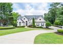 Elegant home with manicured lawn and drive, framed by lush trees at 965 Tiverton Ln, Alpharetta, GA 30022