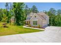 Beautiful two-story home with a two-car garage and a well-manicured lawn nestled in a wooded community on a sunny day at 1013 Liberty Springs Dr, Woodstock, GA 30188
