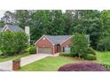 Charming brick home with a well-manicured lawn, mature trees, and an attached two-car garage at 2949 Spotted Pony Nw Ct, Acworth, GA 30101
