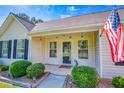 Inviting front porch featuring well-manicured landscaping, and an American flag at 1015 Carriage Way, Loganville, GA 30052