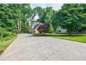 Long concrete driveway leading to a home surrounded by lush greenery and trees at 3620 Chartwell Dr, Suwanee, GA 30024