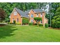 Beautiful brick home featuring a large front yard with mature trees and shrubs at 3620 Chartwell Dr, Suwanee, GA 30024