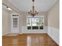 Formal dining room with hardwood floors, chandelier, wainscoting, and large window at 5040 Stonehaven Vw, Cumming, GA 30040