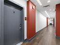 Well-lit hallway with wood floors and contrasting red accents, leading to apartment entrance at 112 Rogers Street Northeast Ne St # 410, Atlanta, GA 30317