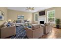 Bright living room featuring hardwood floors, a fireplace, large windows, and stylish furnishings at 2988 Belfaire Lake Dr, Dacula, GA 30019