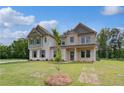 Beautiful two-story home showcasing an inviting front porch and a perfectly manicured green lawn with stone and siding at 157 Haverling Pass, Hampton, GA 30228