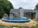 Backyard showcasing a round above ground pool, outdoor seating, lush landscaping, and a covered patio at 123 Chippewa Run, Auburn, GA 30011