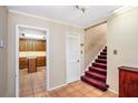 Hallway featuring tile floors, view of kitchen, and stairs with dark red carpeting, accented by white trim at 5491 Valley Brook Road Southeast Se Rd, Mableton, GA 30126