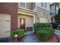 Close-up of townhome entrance, showcasing a stylish front door, manicured shrubs, and convenient two-car garage at 1071 N Village Dr, Decatur, GA 30032