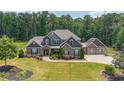 Aerial view of a large home with three-car garage, lush lawn, and mature trees at 265 Enfield Ln, Mcdonough, GA 30252