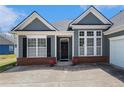 Close up of home exterior with gray wood and brick, a dark front door, and two potted plants at 3634 Cape Ln, Conyers, GA 30013