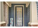 Inviting front entrance featuring a glass door, gray siding, and brick columns with a welcome sign at 2685 Sardis Chase Ct, Buford, GA 30519