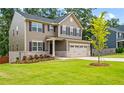 View of a two-story home featuring a well-manicured lawn and a two-car garage at 1049 Climbing Rose Way, Mcdonough, GA 30253