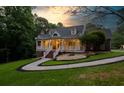 Inviting two-story home with landscaped yard, attractive front porch, and lovely lawn at sunset at 2230 Ewing Chapel Rd, Dacula, GA 30019