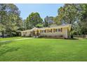 Traditional brick home featuring a lush green lawn, trimmed shrubs, and a quaint covered porch at 3301 Irish Ln, Decatur, GA 30032