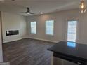 Open-concept living room featuring wood-look flooring, a ceiling fan, and an elegant fireplace at 1672 Fuma Leaf Way, Mcdonough, GA 30252