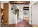 Open hallway featuring brick floor, wooden beams, staircase, and access to other rooms at 4018 Dunbarton Ne Way, Roswell, GA 30075
