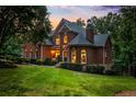 Charming two-story brick home with manicured lawn, mature trees, and warm lighting at sunset at 110 Wellington Way, Canton, GA 30115