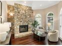 Cozy living room featuring a stone fireplace, hardwood floors, and arched windows for natural light at 110 Wellington Way, Canton, GA 30115