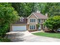 Beautiful two-story house with lush greenery, including trees surrounding the well manicured lawn, and a spacious driveway at 313 Clubhouse Nw Ct, Kennesaw, GA 30144
