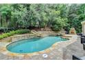 Inviting backyard pool with stone accents, a water feature, and a built-in fireplace for outdoor enjoyment at 5980 Whitestone Ln, Suwanee, GA 30024